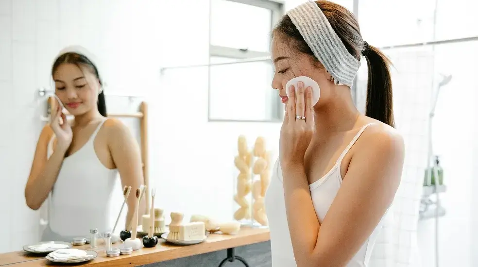 Woman using a personal care product at a bathroom mirror